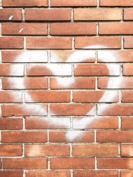 Concept or conceptual painted white abstract love symbol in heart shape, brick wall background, urban and romantic valentine's day metaphor, grunge style.