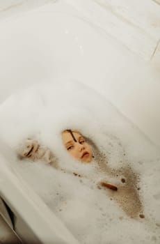 Happy little girl swims in a bathtub full of foam. Only the face is visible from the foam.