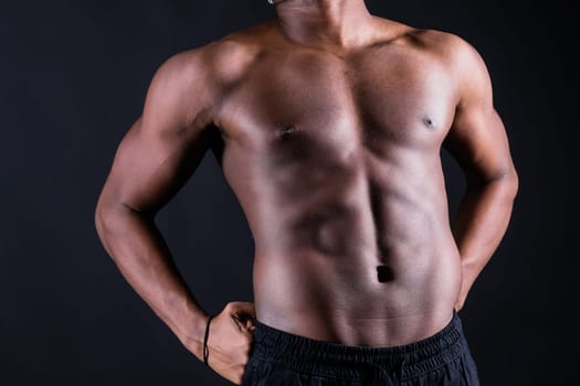 Isolated african muscular man with dumbbells on a dark studio background. Strong shirtless black guy