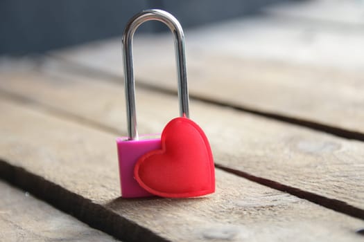 Padlock with a heart on a vintage wooden background.