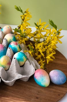 multi-colored Easter eggs on a wooden background, a green background next to yellow flowers.