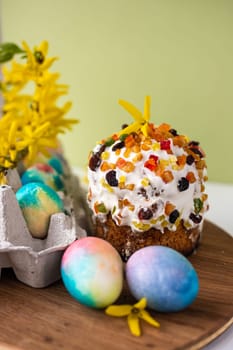 Easter composition with colorful eggs, wooden stand and spring flowers on a yellow background. Easter cake Banner. copy space.