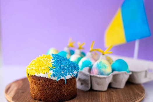 Easter cake decorated in colors of Ukrainian flag and eggs painted in yellow blue, laid out around it. easter concept, ukrainian traditions. Support Ukraine. Selective focus. Ukrainians pray for peace.