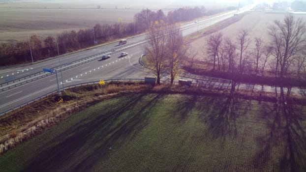 Beautiful Landscape Highway, driving cars, agricultural fields after harvest on sunny autumn day. Top view of automobile road with different cars driving. Sun glare light, highlight. Aerial drone view