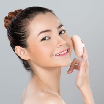 Glamorous beautiful female model applying cushion powder for facial makeup concept. Portrait of flawless perfect cosmetic skin woman put powder puff on her face in isolated background.