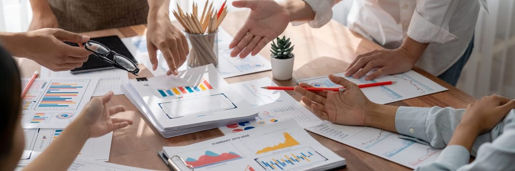 Analyst team utilizing BI Fintech to analyze and pointing at financial dashboard paper office. Businesspeople examining report paper on table for business insight. Panorama shot. Scrutinize