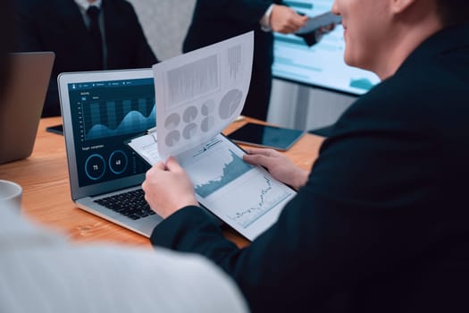 Closeup on BI dashboard on meeting desk with businesspeople analyzing or planning business strategy with hands pointing on financial paper reports as concept of harmony in office workplace.