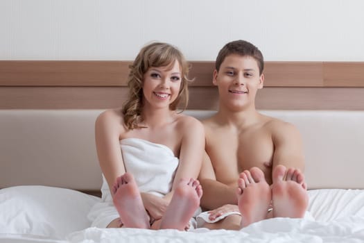 Portrait of cheerful attractive couple sitting in bed, close-up