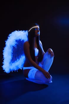 Sexy slim girl with UV makeup posing as angel, close-up