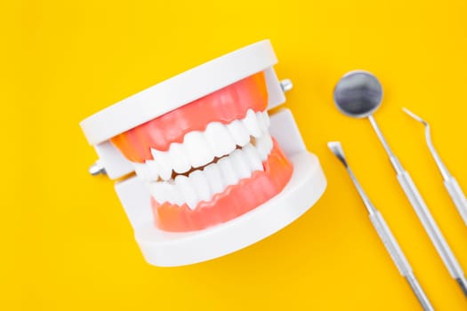 Dentures model and instrument dental on yellow background.