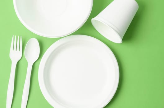 Eco friendly biodegradable paper disposable for packaging food and paper glass on green background.