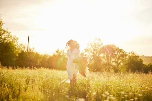 silhouette of a running woman in a light dress running across the field in the rays of the setting sun. High quality photo