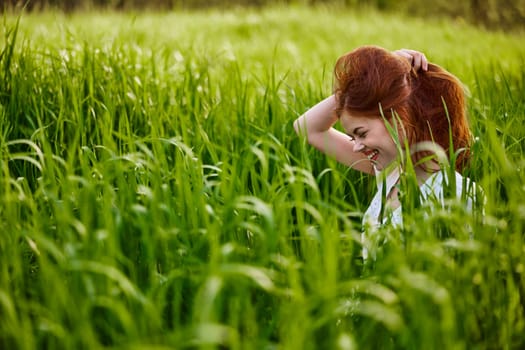 happy woman sitting in tall green grass holding her hair. High quality photo