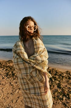 cute woman stands with a plaid during sunset on the beach. Rest, enjoyment. High quality photo