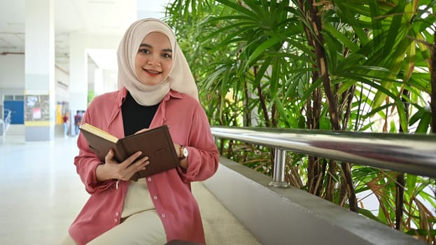 Portrait of Asian muslim student reading book, preparing for exams. Education and youth lifestyle concept.