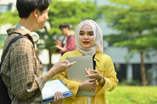 Two university students talking to each other after classes while walking outdoors in university. Education and youth lifestyle concept.