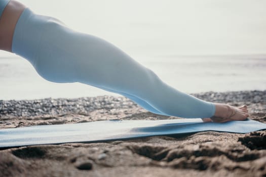 Middle aged well looking woman with black hair doing Pilates with the ring on the yoga mat near the sea on the pebble beach. Female fitness yoga concept. Healthy lifestyle, harmony and meditation.