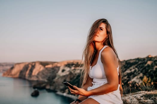 Woman travel sea. Young Happy woman in a long red dress posing on a beach near the sea on background of volcanic rocks, like in Iceland, sharing travel adventure journey