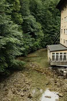 Paper mill surrounded by huge, thick green trees on the Mangfall River in Bavaria, Germany