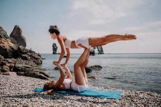 Woman sea yoga. Back view of free calm happy satisfied woman with long hair standing on top rock with yoga position against of sky by the sea. Healthy lifestyle outdoors in nature, fitness concept.