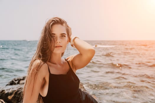 Woman travel sea. Young Happy woman in a long red dress posing on a beach near the sea on background of volcanic rocks, like in Iceland, sharing travel adventure journey