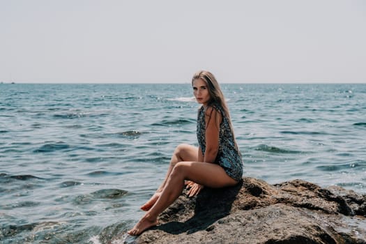 Woman travel sea. Young Happy woman in a long red dress posing on a beach near the sea on background of volcanic rocks, like in Iceland, sharing travel adventure journey