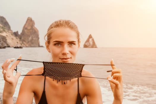 Side view a Young beautiful sensual woman in a mint long dress posing on a volcanic rock high above the sea during sunset. Girl on the nature on overcast sky background. Fashion photo