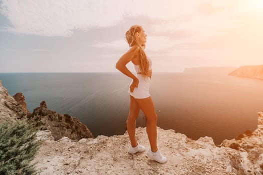 Woman travel sea. Happy tourist in hat enjoy taking picture outdoors for memories. Woman traveler posing on the beach at sea surrounded by volcanic mountains, sharing travel adventure journey