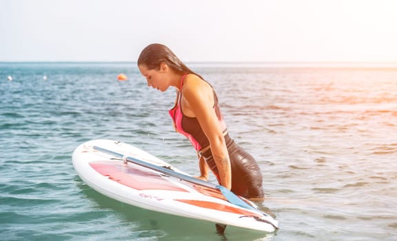 Silhouette of woman standing, surfing on SUP board, confident paddling through water surface. Idyllic sunset or sunrise. Sports active lifestyle at sea or river.