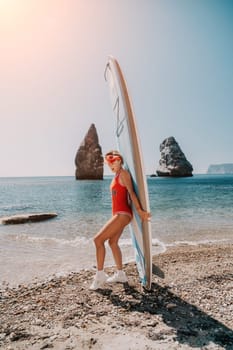 Close up shot of beautiful young caucasian woman with black hair and freckles looking at camera and smiling. Cute woman portrait in a pink bikini posing on a volcanic rock high above the sea