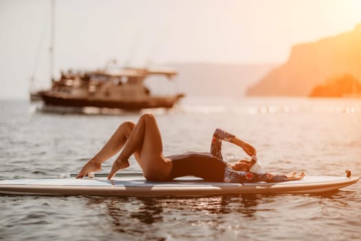 Woman sup yoga. Middle age sporty woman practising yoga pilates on paddle sup surfboard. Female stretching doing workout on sea water. Modern individual hipster outdoor summer sport activity