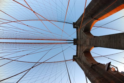 Low angle of Wire ropes of the Brooklyn Bridge against a blue sky in New York