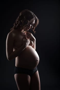 Studio shot of smiling pregnant woman posing topless