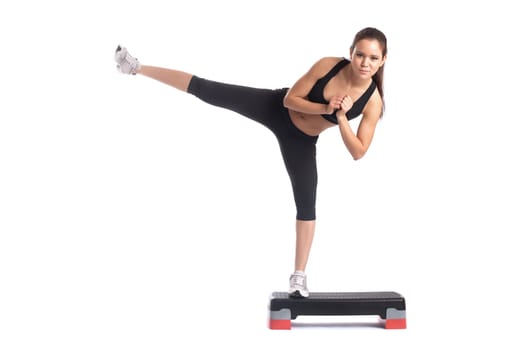 Young slender brunette exercising on stepper in studio