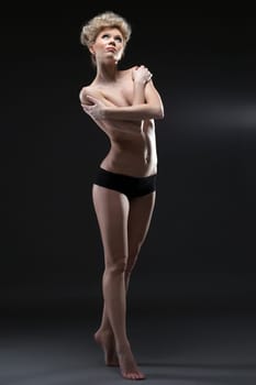 Image of lovely half-naked blonde posing in studio, on gray background