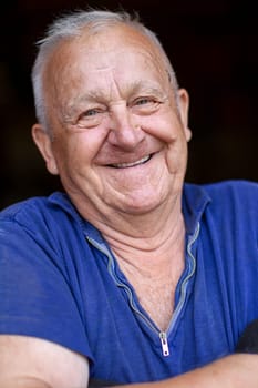 Portrait of an elderly gray-haired man, he looks at the camera and smiles.