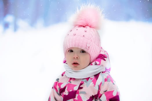 Portrait of a little girl in a winter hat on the background of winter nature. Child in winter.