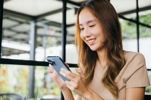 Asian young woman using smart phone for shopping online at cafe coffee shop in the morning, female has transfer money financial internet banking on mobile phone