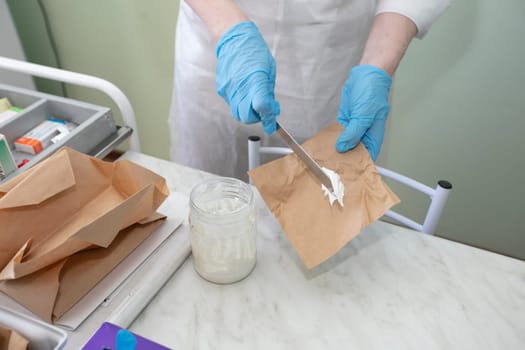 Doctor's hands in gloves hold ointment.