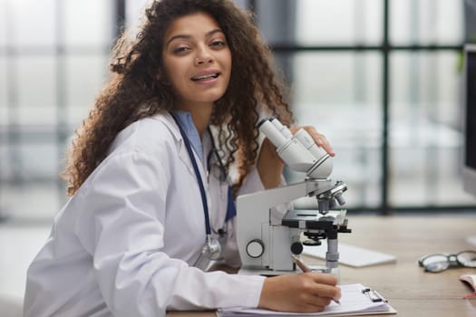 Attractive female scientist looking through a microscope