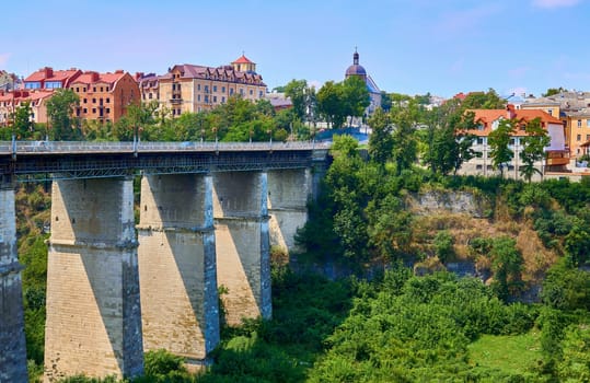 a structure carrying a road, path, railroad, or canal across a river, ravine, road, railroad, or other obstacle. High bridge over a canyon in a summer medieval town.
