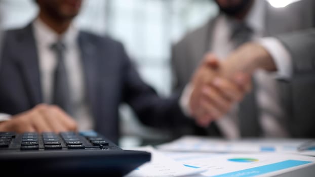 Businessmen shaking hands at the board room table.