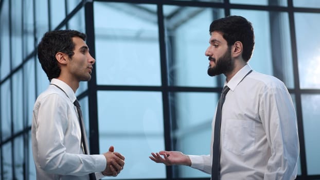 two businessmen discuss the document standing in the office lobby.