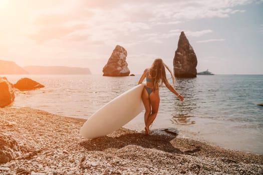 Close up shot of beautiful young caucasian woman with black hair and freckles looking at camera and smiling. Cute woman portrait in a pink bikini posing on a volcanic rock high above the sea