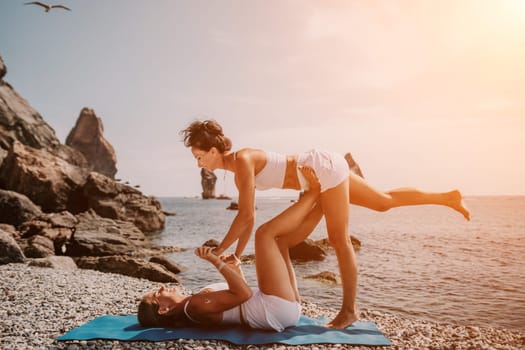 Woman sea yoga. Back view of free calm happy satisfied woman with long hair standing on top rock with yoga position against of sky by the sea. Healthy lifestyle outdoors in nature, fitness concept.