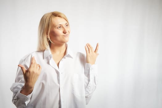 Portrait of a pretty blonde smiling woman posing on white background. Happy girl model in white shirt posing in studio. Copy space