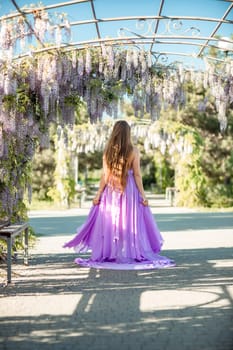 Woman wisteria lilac dress. Thoughtful happy mature woman in purple dress surrounded by chinese wisteria.