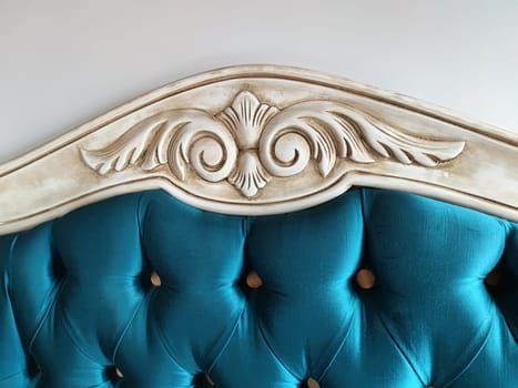 white carved wooden headboard decorated with turquoise satin fabric with Arabic style buttons.