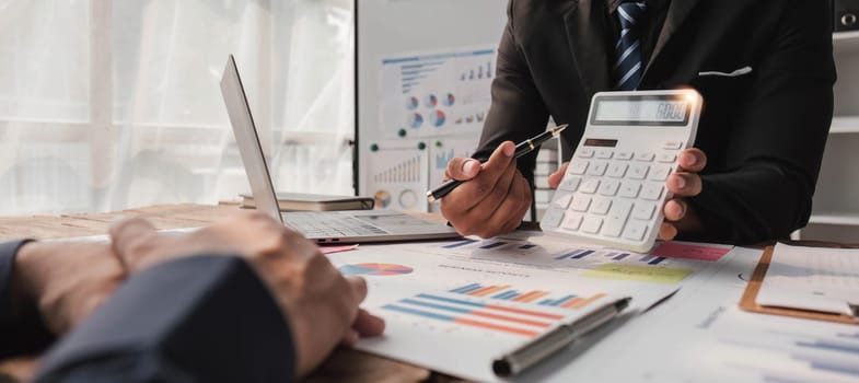 Two business people talk project strategy at office meeting room. Businessman discuss project planning with colleague at modern workplace while having conversation