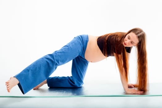 Pleasant pregnant woman posing in profile and trying yoga Young happy expectant relaxing, thinking about her baby and enjoying her future life. Motherhood, pregnancy, yoga concept.